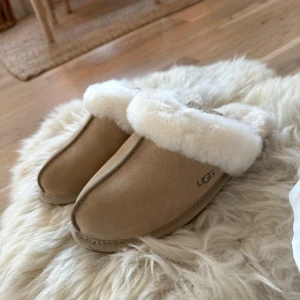 UGG tofflor Scufette II i färgen sand - Säljer dessa Scufette II från UGG då dem var för små för mig och jag returnerade dem inte i tid. Jag har vanligtvis storlek 36 och dessa var små så skulle säga att de passar som en stl. 35. Helt oanvända! Ordinarie pris är 1450kr. Kan skicka dem eller mötas upp i Stockholm eller Uppsala