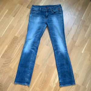 Blå jeans från Replay - Snygga blå jeans från Replay med klassisk femficksdesign, låg midja och coola slitningar. De har en rak passform och är perfekta för en avslappnad stil. 
