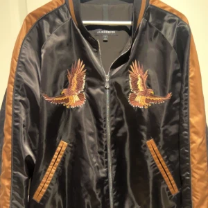 Eagle Varsity Jacket J.Lindeberg Bomberjacka - Snygg svart bomberjacka från J.Lindeberg med broderade örnar på bröstet. Storlek XL med sitter som L. Knappast använd så den är som ny.