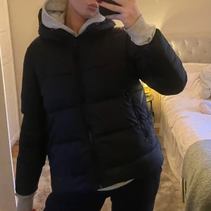 Svart pufferjacka - Säljer en svart pufferjacka med dragkedja och huva. Jackan har långa ärmar och är från Zara. Använd fåtal gånger. I princip helt ny