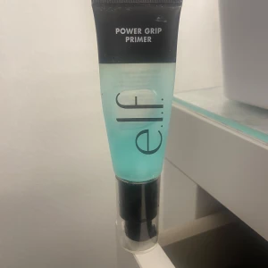 e.l.f. Power Grip Primer - Säljer en e.l.f. Power Grip Primer i en turkos tub. Denna primer hjälper till att hålla sminket på plats hela dagen. Perfekt för en jämn och hållbar bas.
