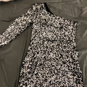 Svart och silvrig one shoulder paljettklänning - Svin snygg one shoulder klänning, perfekt till festligare tillfällen som nyår!! Använt 1 gång 