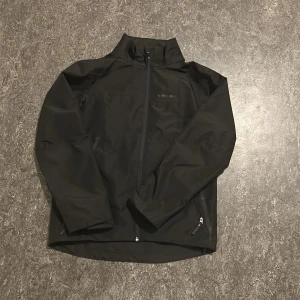 Svart jacka från Everest - Snygg svart jacka från Everest med dragkedja framtill och hög krage. Perfekt för kyligare dagar med sin stilrena design och praktiska fickor med dragkedja. Jackan har långa ärmar och är tillverkad i ett slitstarkt material.