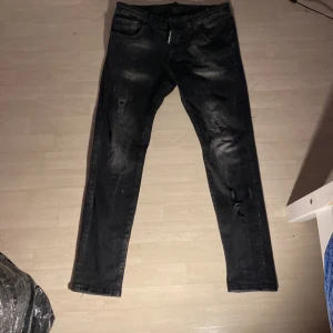 Svarta jeans från Dsquared2 - Snygga svarta jeans från Dsquared2 med slitna detaljer och en cool tvätt. De har en klassisk femficksdesign och knappgylf. Perfekta för en trendig look.