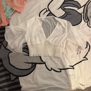Vit blus med prickigt mönster - Säljer en söt vit blus med prickigt mönster och v-ringning. Blusen har trekvartsärmar och en smockad midja som ger en fin passform. Perfekt för vår och sommar! Den har ingen tagg men jag gissar storleken är S
