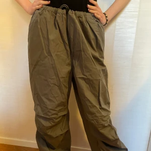 Gråa fallskärmsbyxor🩶 - Från H&M i storlek M. Aldrig använda så i nyskick & prislapp är kvar. Snygga gråa fallskärmsbyxor med loose fit och Byxorna har en elastisk midja med dragsko för justerbar passform, även justerbart vid fotlederna. Två fickor fram & två fejk fickor baktill. Original pris 249kr men säljer för 149kr. Perfekta för en street stil eller dansa med😊