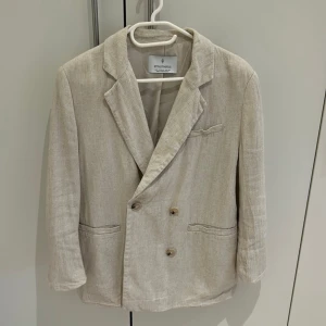 Beige kavaj från Stradivarius - Snygg beige kavaj från Stradivarius med klassisk design och dubbelknäppning. Perfekt för en stilren look. Tillverkad i ett lätt och bekvämt material.