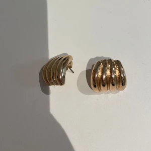 Guldiga örhängen med räfflad design från Gina - Kommer tyvärr aldrig till användning.