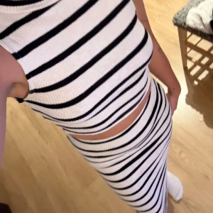 Randig ärmlöst set - Snygg ärmlöst set med svartvita ränder. Den har en croppad topp och en lång kjol som ger en modern look. Perfekt för en stilren och avslappnad stil.