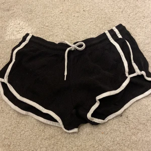 Svarta shorts med vita detaljer från Primark - Säljer ett par svarta shorts från Primark i storlek XS. De har vita kanter och en bekväm dragsko i midjan. Perfekta för en avslappnad stil.