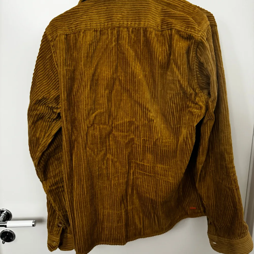 Snygg brun manchester overshirt från Ciszere med klassisk krage och knappar framtill. Två bröstfickor med knappar ger en cool look. Perfekt för lager-på-lager stil under höst och vår. I mycket bra skick använd 1-2 gånger. Storlek M. Paidat.