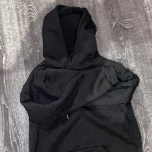 Svart hoodie - Säljer en klassisk svart hoodie med luva. Perfekt för en avslappnad stil och passar till det mesta. Den har en stor ficka framtill och är gjord i ett mjukt material.