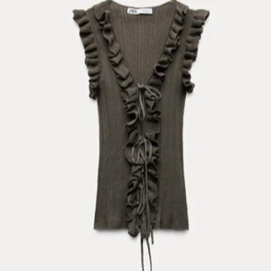 Grön Zara volangtopp! - Snygg grön ribbad topp från Zara med volangdetaljer och knytning framtill. Toppen är ärmlös och har en v-ringad design som ger en trendig look. Perfekt för att styla med jeans eller kjol. Eftertraktad och helt slutsåld!! Storlek M men passar mig som brukar ha S! 💕prislapp finns kvar så är helt oanvänd! Pris kan diskuteras!