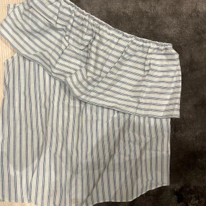 Randig kjol i blått och vitt - Snygg och luftig kjol med blå och vita ränder. Kjolen har en omlott-design och elastisk midja för bekväm passform. Perfekt för varma dagar och ger en avslappnad stil. Passar mig i m/s