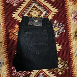 Svarta jeans från Armani - Snygga marinblå jeans från Armani med klassisk femficksdesign. De har en rak/slim passform och är tillverkade i ett slitstarkt material. Perfekta för en stilren look. Priset går ner vid snabb affär! 