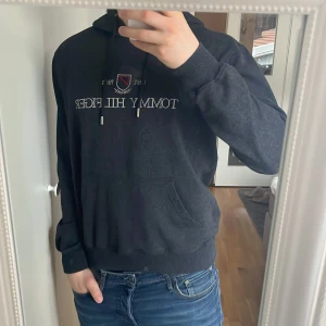 Mörkgrå hoodie från Tommy Hilfiger - Snygg mörkgrå hoodie från Tommy Hilfiger. Det står storlek Xl i tröjan man passar M