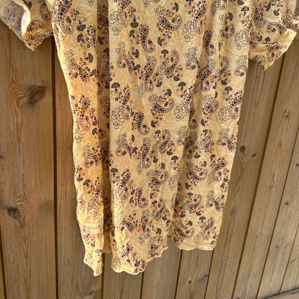Charmig gul topp med blommigt mönster. Den har korta ärmar och en luftig passform, perfekt för varma dagar. Klänningen är gjord i ett lätt material som ger en skön känsla. Från märket Odd Molly i storlek 1 som enligt deras storleksguide motsvarar en storlek S. Helt ny med tags. . Yläosat.