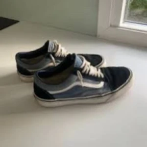 Svart och blå sneakers från Vans - Snygga Vans sneakers i svart och blått med vit sula och snörning. Perfekta för en avslappnad stil.