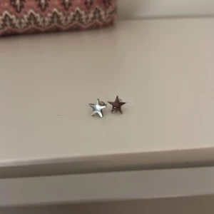Stjärnformade örhängen i silver  - Säljer ett par stjärnformade örhängen i silver. Perfekta för att lägga till en subtil touch av stil till din outfit. De är små och diskreta, vilket gör dem lätta att bära varje dag. (I rostfritt stål)