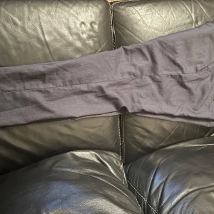 Grå kostymbyxor från Tiger of Sweden - Snygga grå kostymbyxor från Tiger of Sweden. Byxorna har en klassisk design med hällor för bälte och en knappdetalj på bakfickan. Perfekta för en stilren look.