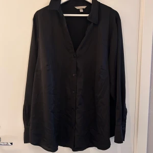 Blus  - Satinblus med knappar framtill och vid ärmarna 