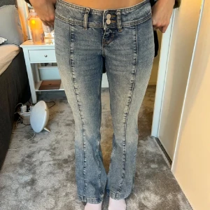 Blå bootcut jeans - Snygga blå bootcut jeans med låg midja och klassisk femficksdesign. Jeansen har en lätt tvättad look och stängs med dragkedja och knapp. Perfekta för en avslappnad stil. Sparsamt använda🩷