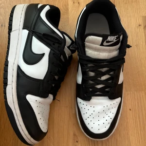 Svartvita Nike Dunk sneakers, strlk 43 - Nike Dunk Low i svart och vitt. Skorna är i gott skick med normala användningsmärken. Se detaljbilder på creases. Storlek 43. Kommer i originalkartongen.   Säljer för sonen har vuxit ur dem.