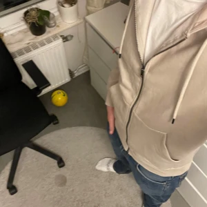Beige hoodie från Jack & Jones - Säljer en stilren beige hoodie från Jack & Jones. Den har dragkedja framtill och en klassisk huva med snörning. Perfekt för en avslappnad look. Storleken är inte specificerad, men den ser ut att ha en normal passform.     Har aldrig använts förutom när jag tog bilden. Ny pris 600kr