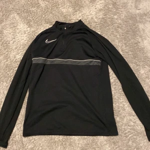 Svart långärmad tröja från Nike - Snygg svart långärmad tröja från Nike med en diskret grå rand över bröstet. Har 2 stycken och kan sälja den andra också för ett bra pris.