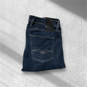 Mörkblåa Replay Anbass Jeans – W33 L34 - Säljer ett par mörkblåa Replay Jeans i modellen Anbass, storlek W33 L34. Jeansen är i mycket fint skick med minimal användning, vilket gör dem perfekta för både vardag och mer uppklädda tillfällen.