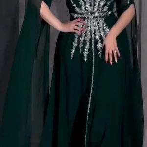 Mörkgrön klänning med glittriga detaljer - Elegant mörkgrön långklänning med glittriga silverdetaljer som strålar ut från midjan. Klänningen har långa ärmar och ett flödande tyg som ger en dramatisk effekt. Perfekt för en glamorös kväll.