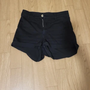 Svarta shorts från Divided - Säljer ett par svarta shorts från Divided. De har en dragkedja framtill och knappstängning. Perfekta för sommardagar eller en avslappnad stil.