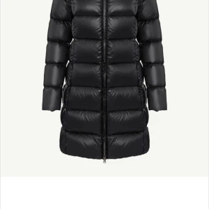 Svart dunjacka med dragkedja - Snygg och varm svart dunjacka med dragkedja. Jackan har en lång passform och är perfekt för kyliga dagar. Den quiltade designen ger extra stil och komfort.