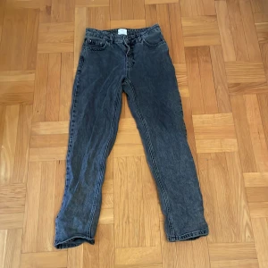 Mörkgrå jeansbyxor från Grunt - Säljer ett par mörkgrå jeansbyxor från Grunt i modellen 'Street Loose'. Byxorna har en loose passform och är perfekta för en avslappnad stil. De har klassisk femficksdesign och knappgylf. Storlek 26/158