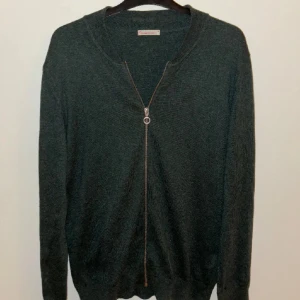 Mörkgrön kofta från Knowledge Cotton Apparel - Snygg mörkgrön kofta från Knowledge Cotton Apparel med dragkedja framtill. Perfekt för lager-på-lager och har en klassisk look med ribbade kanter. Mycket fint skick, knappt använd.