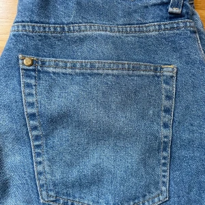 Blå jeansbyxor från Big John - Snygga blå jeansbyxor från Big John med klassisk design. Byxorna har en hög midja och raka ben, vilket ger en tidlös look. Perfekta för en avslappnad stil. Töjbar, kan användas som låg-/högmidjat.