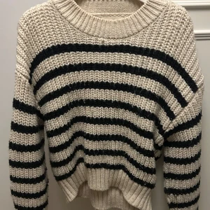 Randig stickad tröja från H&M - Säljer en mysig stickad tröja från H&M i beige och svart. Tröjan har ett randigt mönster och långa ärmar. 