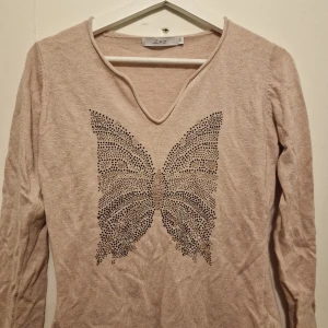 Tröja med fjärilstryck - Fin tröja från 2Biz med en glittrig fjäril framtill. Garderobsrensning så kika gärna på övriga auktioner.