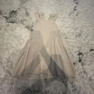 Beige top - Säljer en stilren beige top med ärmlös design. Perfekt för varma dagar med sin luftiga passform och enkla stil.