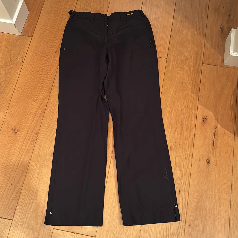 Svart regnställ (Gore tex) från J.Lindeberg med hög krage och dragkedja. Perfekt för golf eller promenad i lite dåligt väder.. Takit.