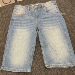 Blå jeansshorts - Säljer ett par klassiska blå jeansshorts. Shortsen är knälånga  och är i mycket bra skick, använd två gånger.