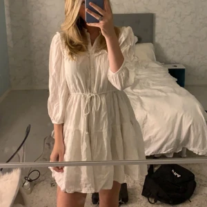 Vit klänning med knytband och fina detaljer  - Säljer min jätte fina vita klänning med knytband i midjan och trekvartsärmar. Denna klänning är köpt ifrån Holly & White på lindex, måste tyvärr sälja denna klänning då den är för kort🩷Den är använd ungefär 4 gånger🩷Pris går att diskutera 