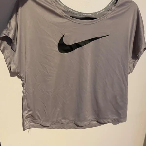 Grå t-shirt från Nike - Snygg grå t-shirt från Nike med den svarta swoosh-loggan på framsidan. Perfekt för alla olika aktiviteter. Kortärmad och i ett mjukt material. Använd några få gånger, så den är i ett väldigt bra skick! Tröjan är i storlek M