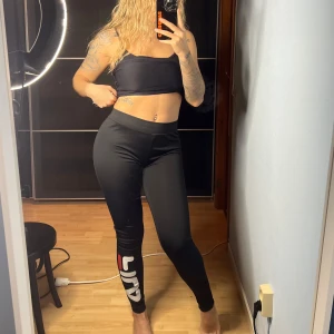 Svarta träningstights FILA - Snygga svarta träningsleggings från FILA. Perfekta för träning eller en avslappnad dag. De har en tight passform och är tillverkade i ett stretchigt material för bästa komfort. Passar både S och M. Oanvända.