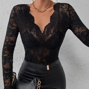 Svart spetsblus - Elegant svart spetsblus med långärmad design och djup v-ringning. Perfekt för en stilfull kvällslook.