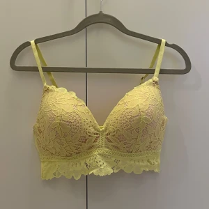 Gul spets-BH från Hunkemöller - Säljer en söt gul BH från Hunkemöller med vacker spetsdetalj. Helt oanvänd då den var lite för liten på mig.💛