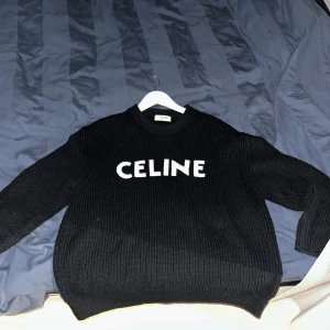 Svart stickad tröja från Celine - Säljer en stilren svart stickad tröja från Celine med vit logotyp på bröstet. Tröjan har en klassisk rund hals och långa ärmar, perfekt för en trendig look. Passar bra till både jeans och kjol. Hör av dig vid intresse! Bra skick och nypris ligger på 12 000kr. Storlek S men passar bra för mig och jag är 180 och brukar ha L