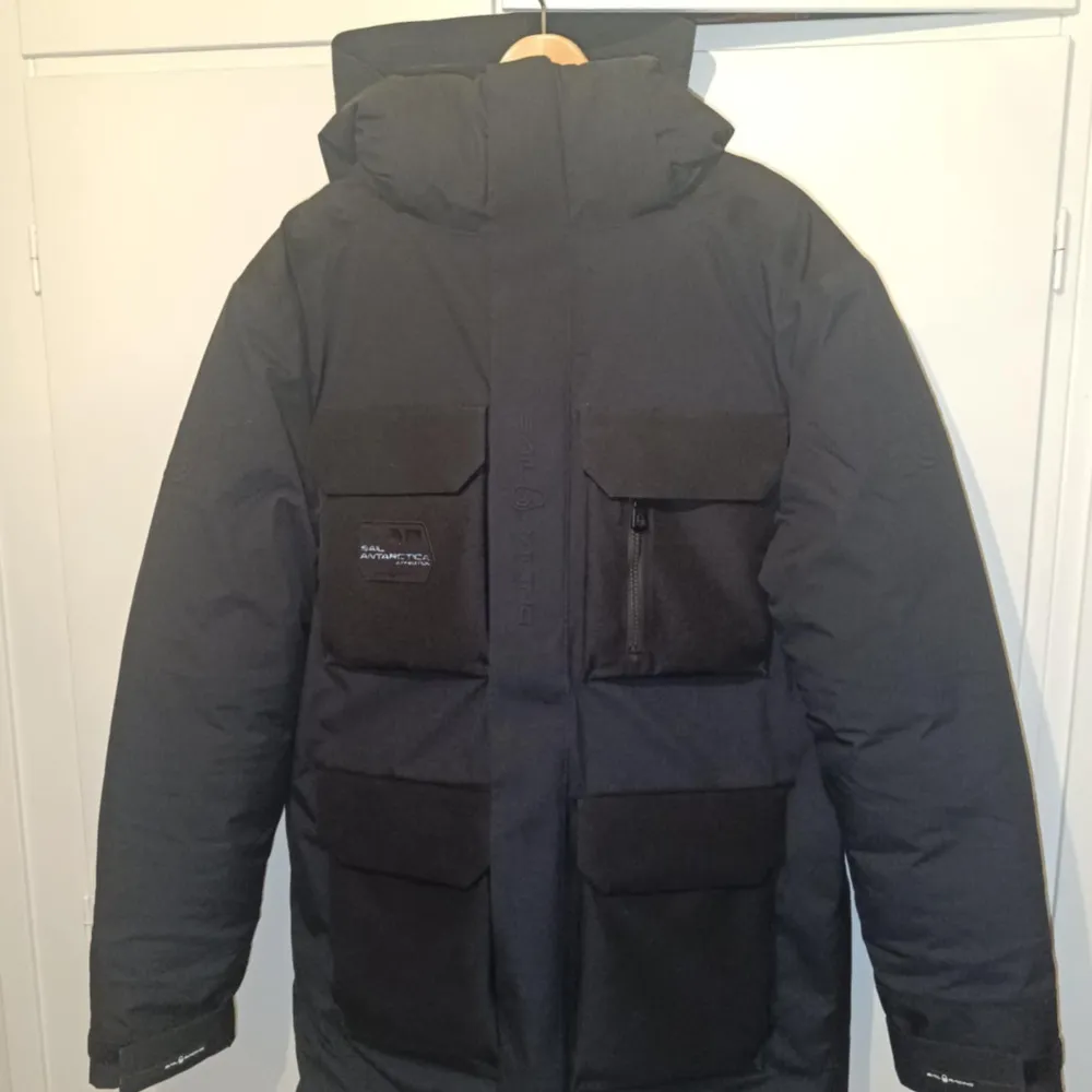 Säljer en nästintill oanvänd svart Gore-Tex jacka från Sail Racing. Jackan har flera praktiska fickor med dragkedjor och en quiltad insida för extra värme. Perfekt för kalla och blöta dagar med sin vattentäta och vindtäta design. Den har en hög krage och justerbar huva. Säljer pga för stor i storleken.. Takit.