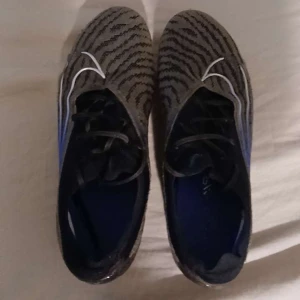  Fotbollskor Nike mercurial  - Snygga fotbollsskor med ett iögonfallande zebramönster i svart och grått. Skorna har snörning och en blå sula som ger en cool kontrast. Perfekta för fotbollsplanen och för den som vill sticka ut. Nike mercurial använda 2 gånger 