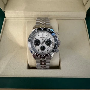 Seiko Panda - Säljer en stilren silverfärgad klocka från Seiko med vit urtavla och svarta subdialer. Klockan har en tvåfärgad bezel i svart och blått samt en länkarmband i rostfritt stål. Perfekt för den som gillar en klassisk och tidlös design.